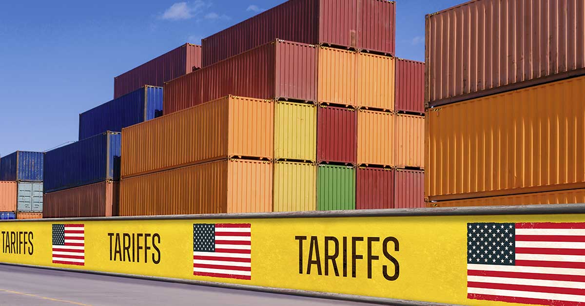 Stacked shipping containers behind tariff barriers with US flags, symbolizing trade war