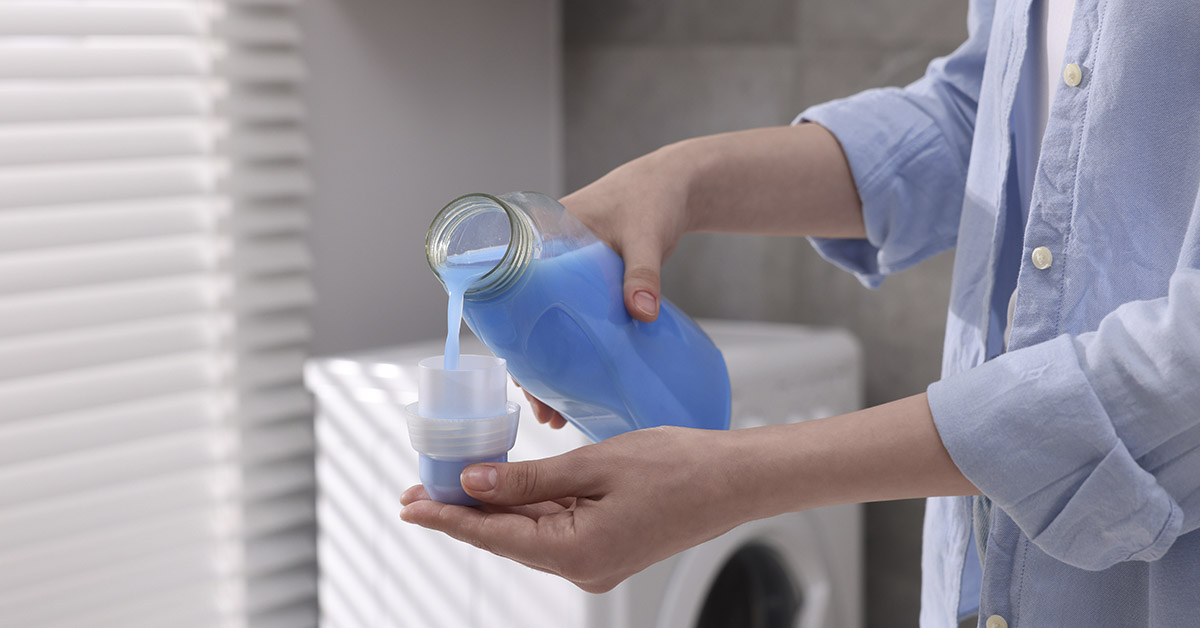 woman pouring fabric softener into measuring cap