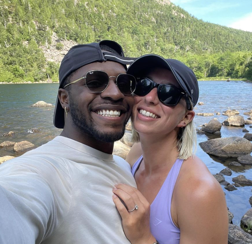 Charles and Sydney Rogers taking a selfie together by a lake with mountains in the background.