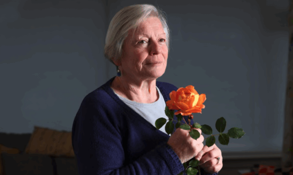 Joy Milne, the woman who smells illness, holds an orange rose. Her sensitive nose first detected her husband's Parkinson's disease through scent changes.