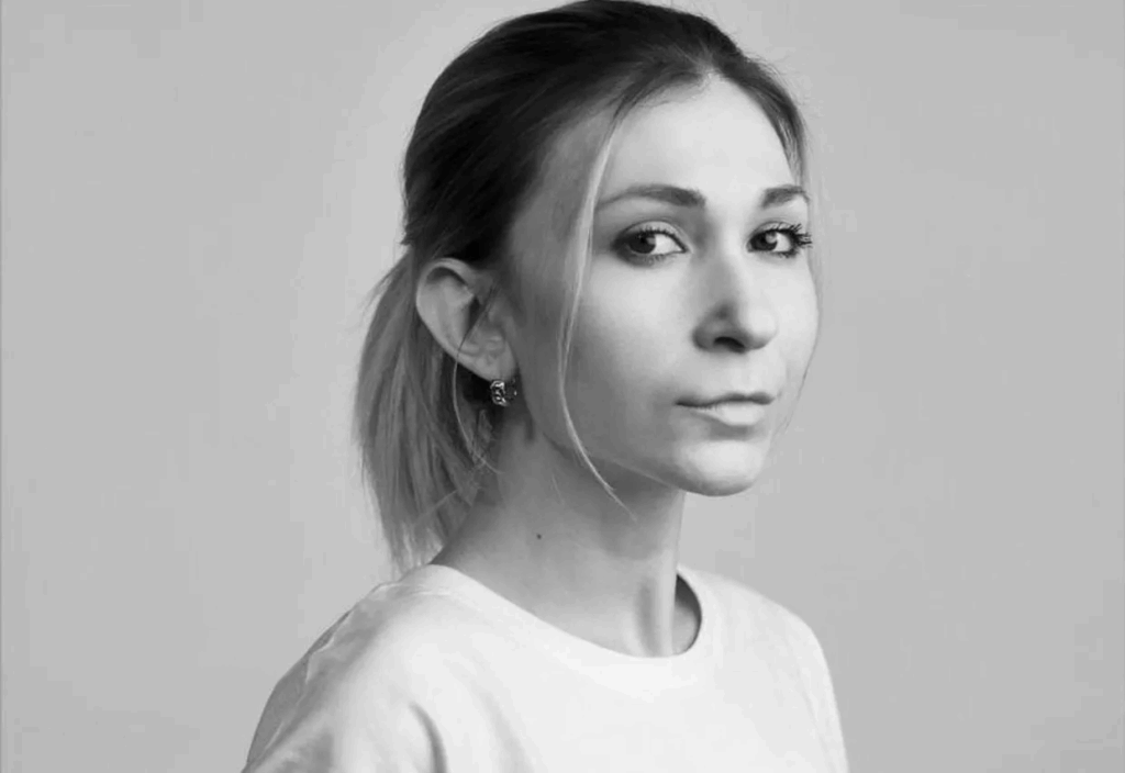 Black and white portrait photograph of Ukrainian journalist Viktoriia Roshchyna showing her looking directly at the camera with a solemn expression. She has light hair pulled back with some strands framing her face, and is wearing a light-colored top. This brave journalist was held in the detention centre in Taganrog where captors subjected her to extreme cruelty before her death in Russian custody.