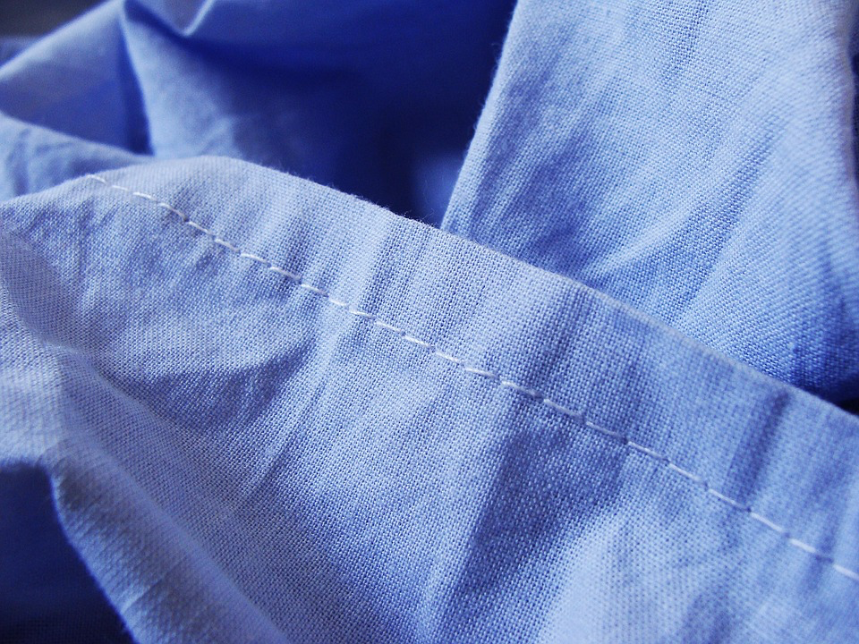Close-up texture of blue fabric showing fine stitching and weave pattern, representing how clothing choices can impact the amount of synthetic microfibers released into the environment.