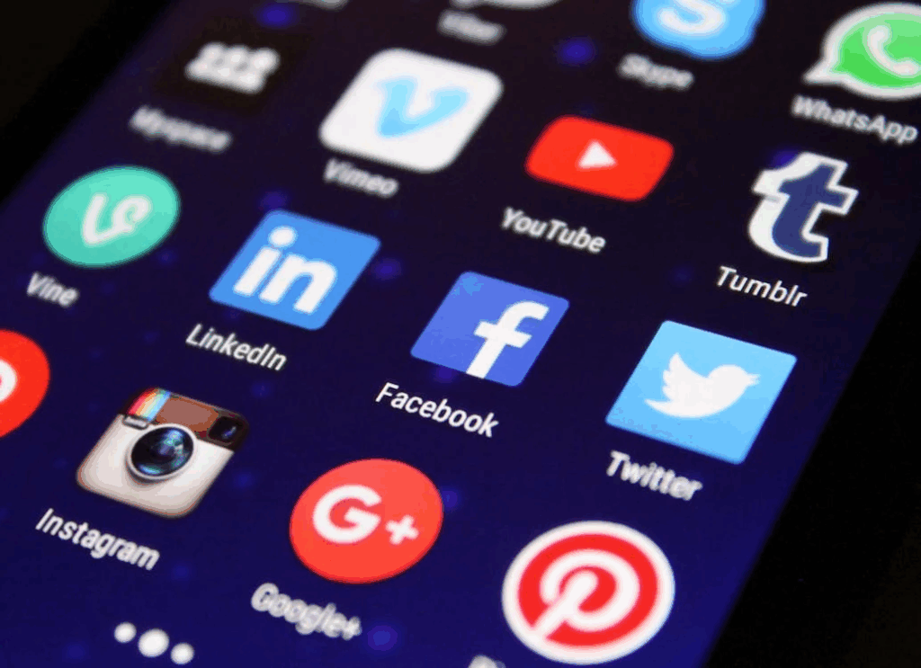 A close-up of a smartphone screen displaying various social media app icons from around 2011, including Instagram (with its older camera logo), Facebook, Twitter, YouTube, WhatsApp, Tumblr, LinkedIn, Google+, Pinterest, and Vine. This represents the early social media landscape when photo sharing was beginning to become more mainstream, as referenced in the article's section on how social media changed photography.
