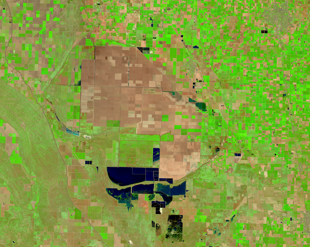 Aerial imagery from March 16, 2024 depicting the significantly reduced water coverage in the basin. Most farmland has reemerged as the lake receded to approximately 4,500 acres, showing the transition back to agricultural use with geometric field patterns in varying shades of brown and green surrounding the remaining water.