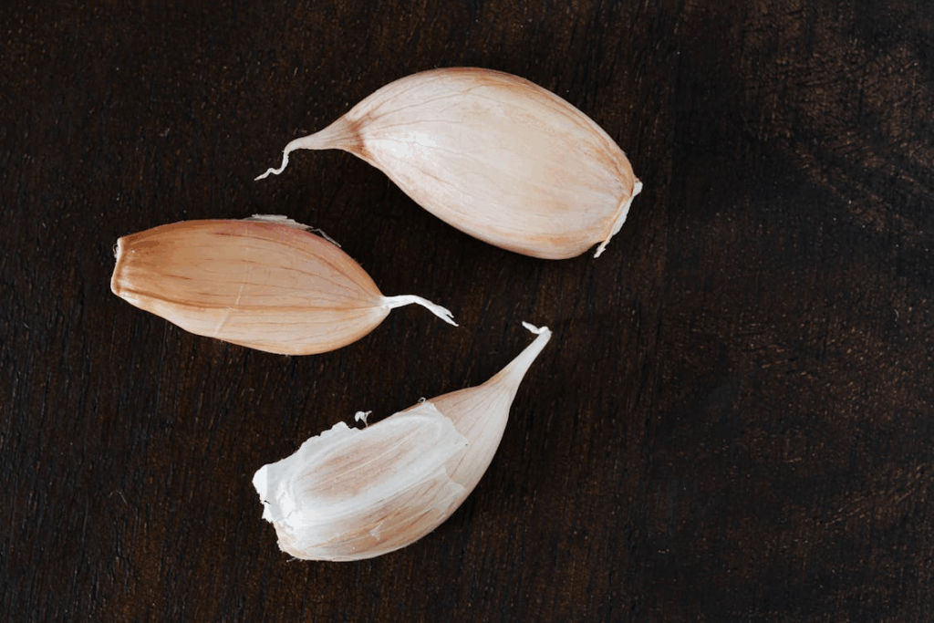 Set of whole fresh cloves of garlic arranged on wooden tabletop in kitchen