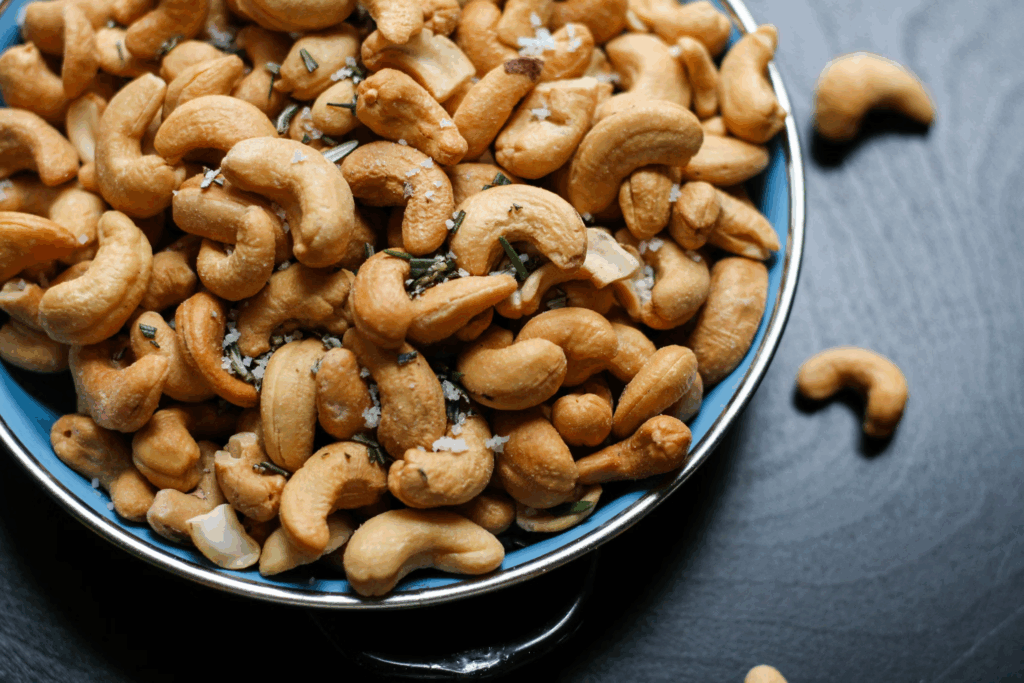 Bowl of roasted cashews with herbs and salt on a blue plate, these mood-boosting foods contain magnesium and zinc that naturally soothe anxiety.