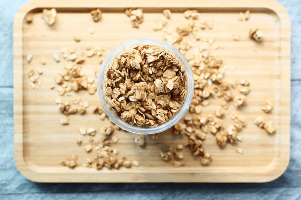 Glass jar of rolled oats on wooden tray, providing steady energy that prevents mood swings and helps the brain produce serotonin.