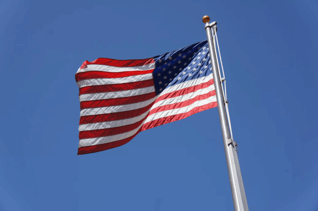 The American flag flying against a clear blue sky, symbolizing property rights and legal protections afforded to homeowners under United States law, where adverse possession rights vary by state.