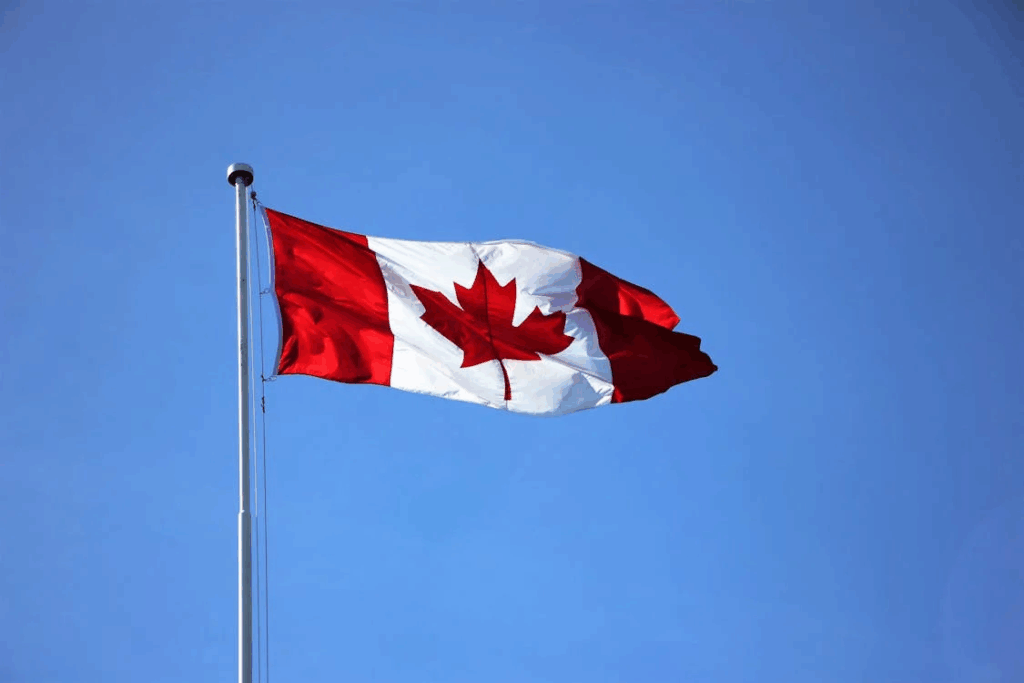 The Canadian flag waving in the breeze against a blue sky, representing Canada's provincial approach to adverse possession laws, where unauthorized occupants typically need 10-30 years of continuous occupation.