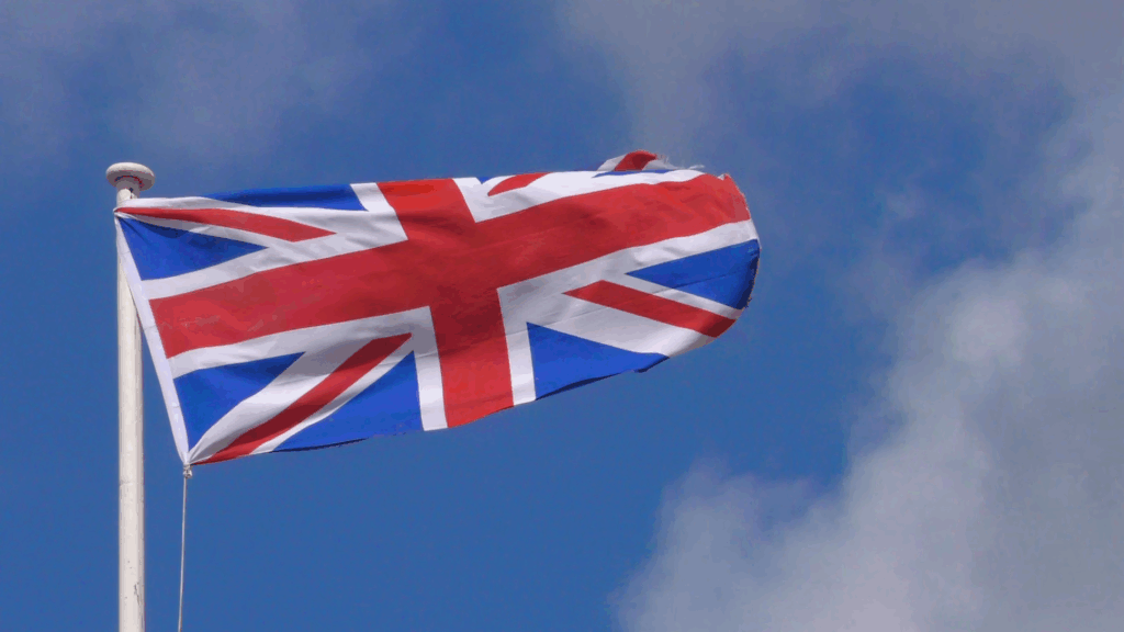 The Union Jack (British flag) flying against a partly cloudy sky, representing the United Kingdom's approach to unauthorized occupation, where residential trespassing became criminalized in 2012.