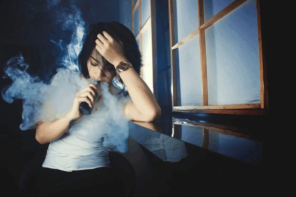 Young woman smoking e cigarette in darkness