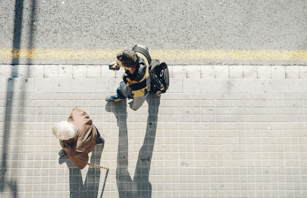 Two people walking in the same direction on a paved sidewalk, viewed from above, showing how walking works for everyone regardless of age or fitness level as recommended by heart doctors.