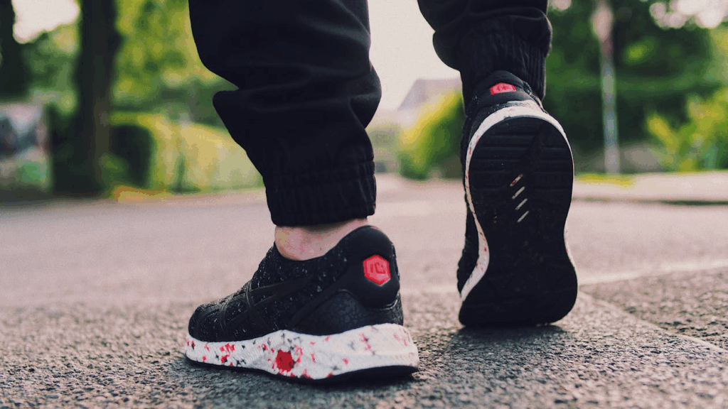 Person's feet in athletic shoes mid-stride on pavement, demonstrating the brisk walking pace above 3 mph that provides the most heart-protective benefits.