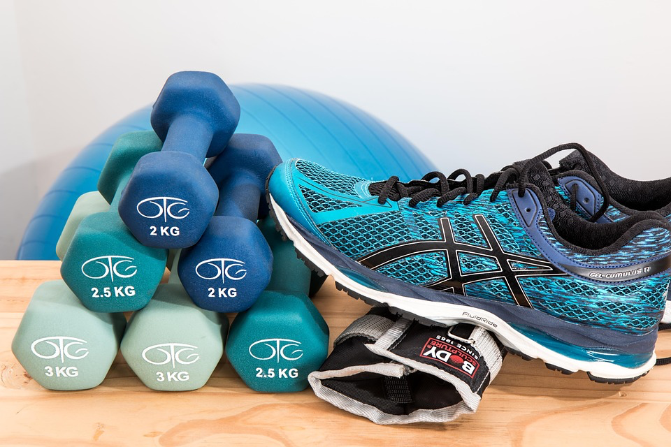 Dumbbells, running shoes, and exercise equipment arranged together, showing how combining walking with light strength training creates the perfect combo for exercise for heart health.
