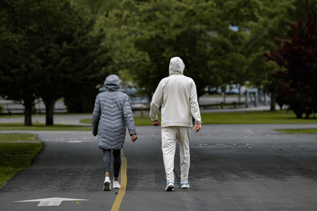 Two people walking together on a tree-lined path, showing how you can make walking a safe and enjoyable exercise for heart health by starting slowly and walking with others.