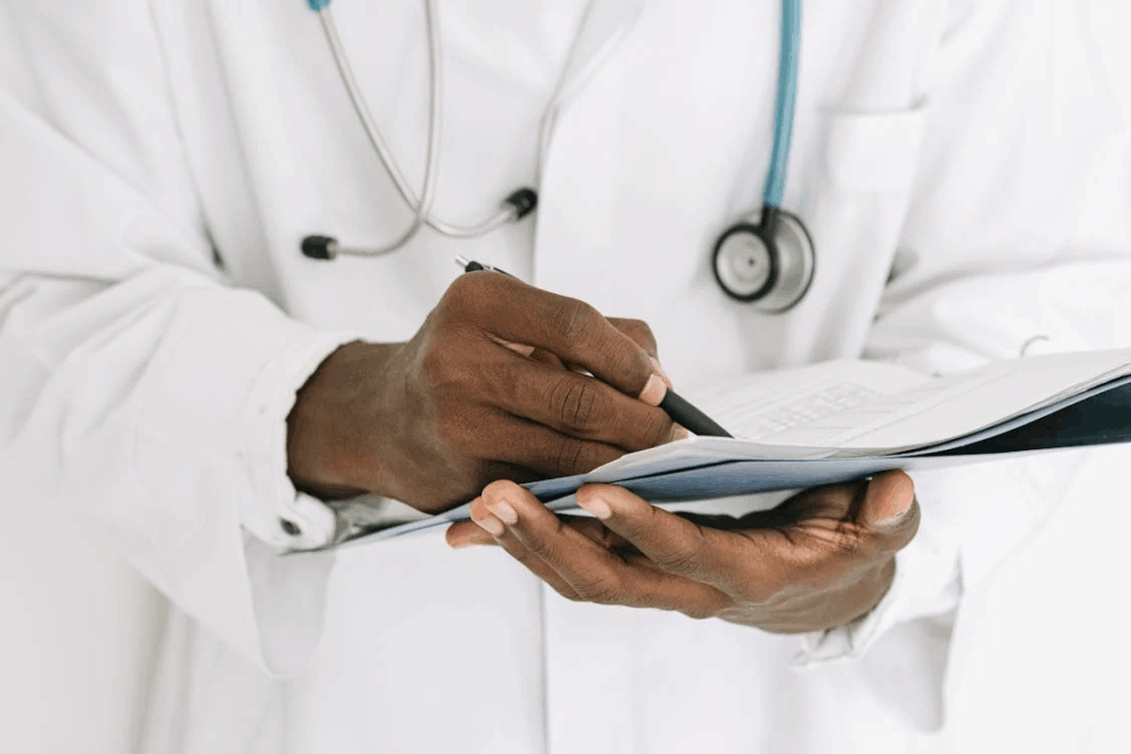 Doctor's hands writing on medical charts with stethoscope, showing medical professionals studying cases like Brianna's.
