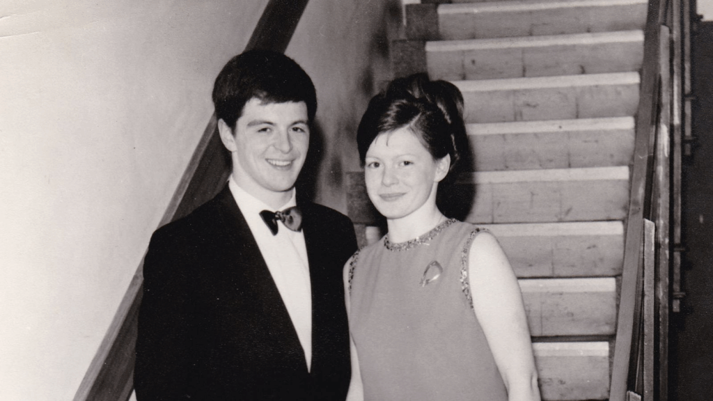A vintage photo of Joy and Les Milne in formal clothes on stairs. This shows when she first fell in love with his natural scent.