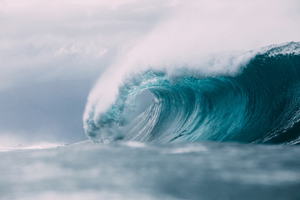 Massive ocean wave curling with white foam spray showing the deadly power that creates killer tsunamis when earthquakes strike underwater.
