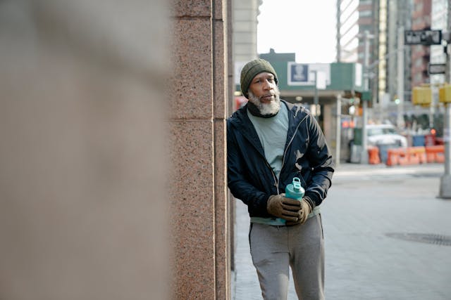 old person leaning against wall