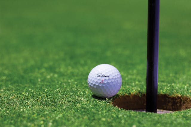 Gold ball near hole on golf course