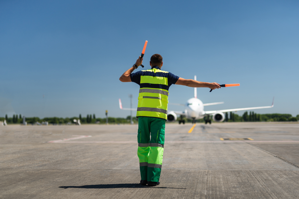 Time for landing. Aviation marshaller meeting passenger plane at the airport
