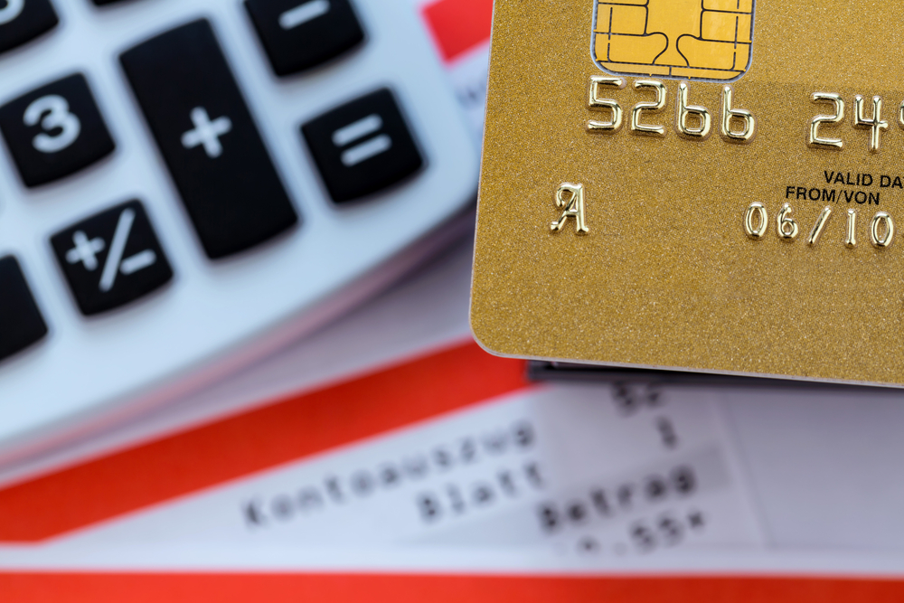 a gold credit card, bank statement and calculator. symbolic photo for cashless transactions and status symbols.