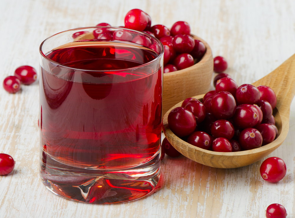 Cranberries in a wooden spoon and glass of juice. Selective focus