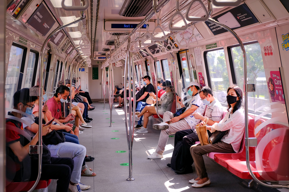 Singapore May2020 COVID-19 MRT train. Passengers wearing masks on public transport. Train uncrowded during coronavirus outbreak. Social distancing observed; stickers and markings on floor.