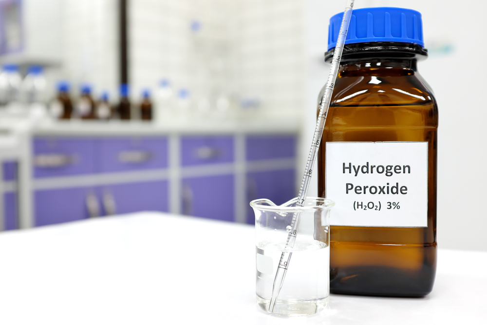 Selective focus of hydrogen peroxide solution in brown amber bottle. Blur laboratory background with copy space.
