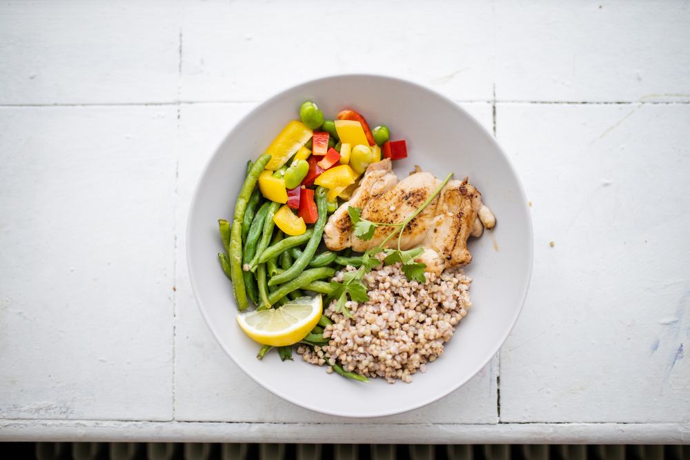 Chicken and buckwheat dish with green beans, broad beans, tomato, and pepper slices from above. Nutritious dish with vegetables and meat. Healthy balanced diet