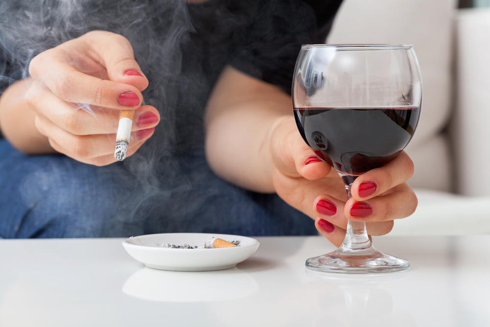 Woman is smoking cigarette and drinking alcohol