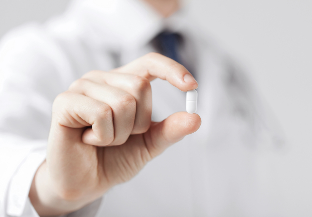 healthcare and medical concept - doctor with pill in hospital