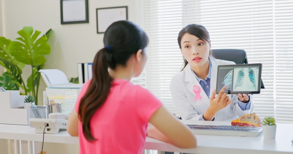 asian woman has breast cancer diagnosis in hospital - female doctor showing mammography test results and xray to patient on digital tablet