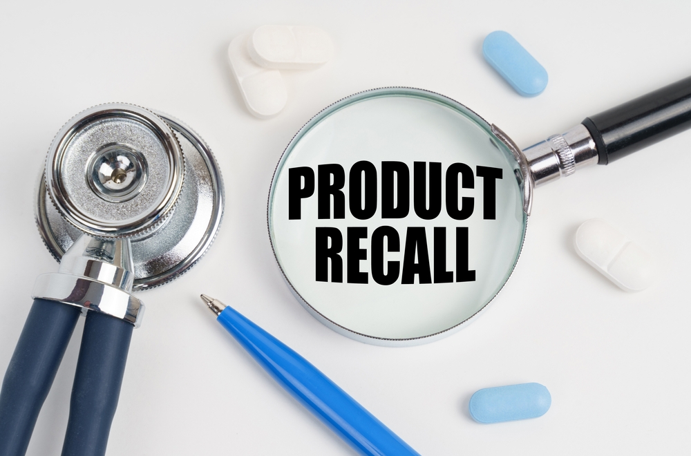 Medicine and health concept. On a white surface lie pills, a pen, a stethoscope and a magnifying glass with the inscription - PRODUCT RECALL