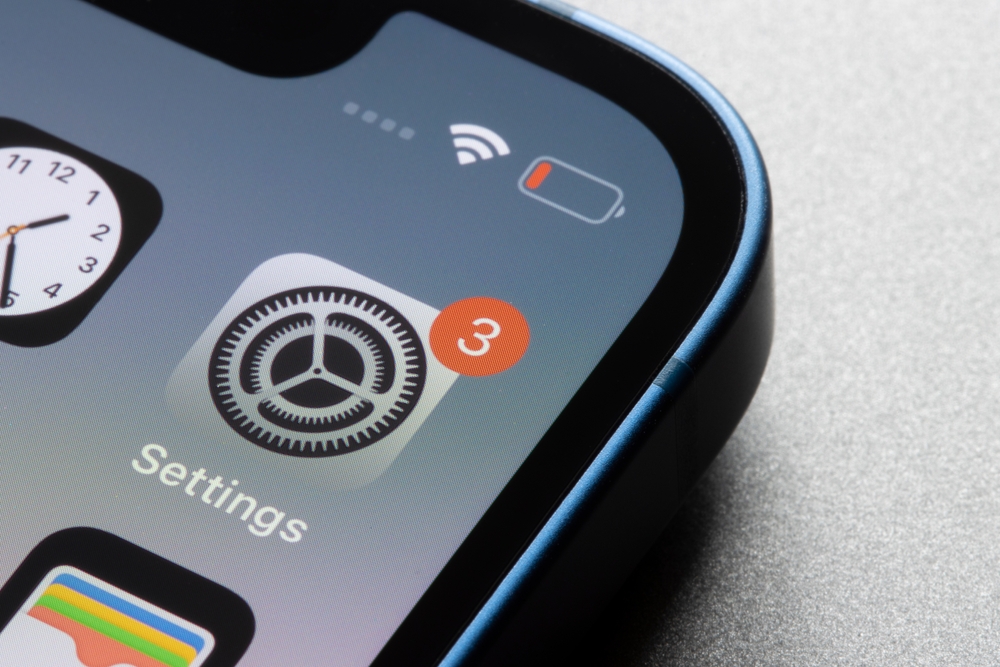 Portland, OR, USA - Feb 14, 2022: Closeup of the iOS Settings app icon with a notification badge seen on an iPhone 13 mini.