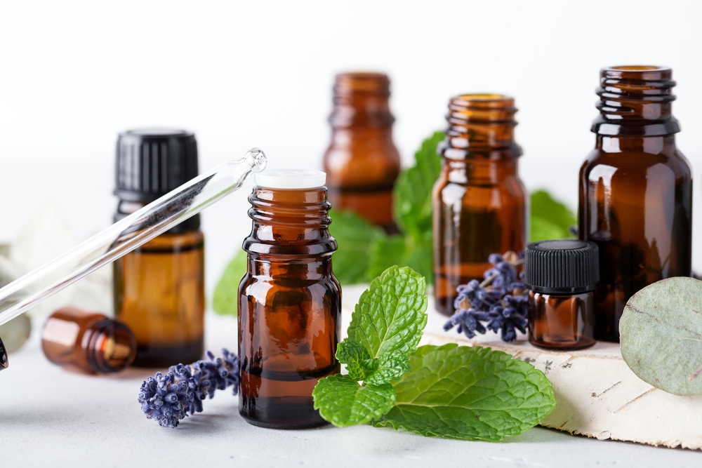 Different essential oils in dark amber bottles and glass dropper, mint leaves and lavender flowers product ingredients. Concept of aromatherapy and alternative medicine
