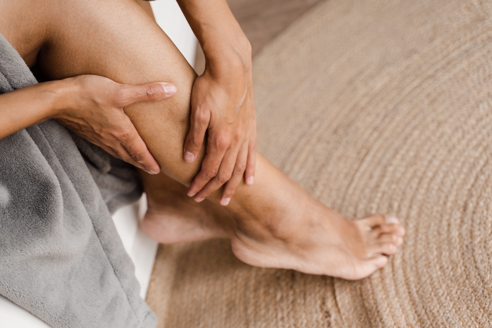 Sclerotherapy procedure at visiting vascular surgeon doctor. Deep vein thrombosis and varicose of african woman. Girl touching her legs and looking at veins