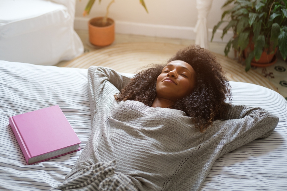Relaxed woman daydreaming and resting in her bed in the morning at home. Relax and tranquility concept.