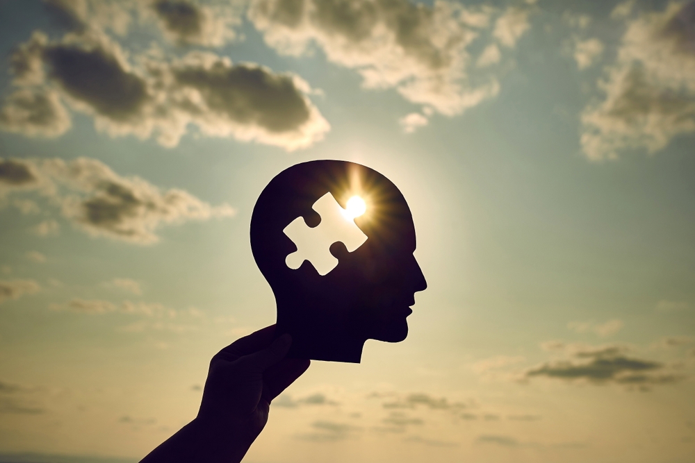 Concept of a human head with a puzzle in the middle. Finding a solution in the human brain. Concept of cognitive rehabilitation in Alzheimer's disease and dementia patien. Mental health.