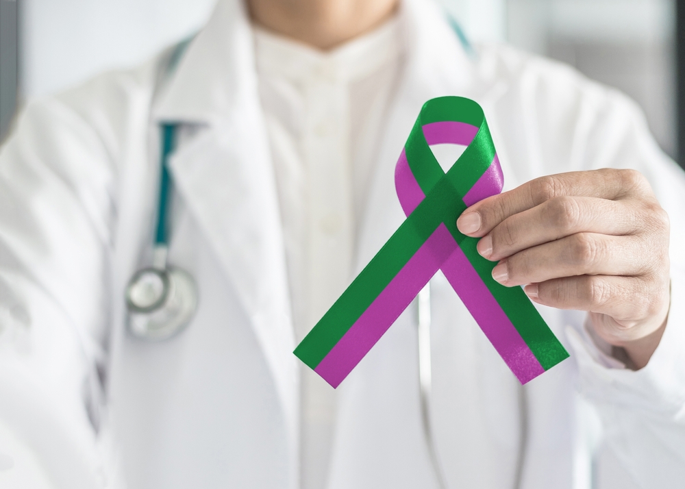 Anal cancer awareness and Stickler Syndrome with green purple ribbon raising awareness on health and illness month with bow color on surgical doctor gown in clinic or hospital