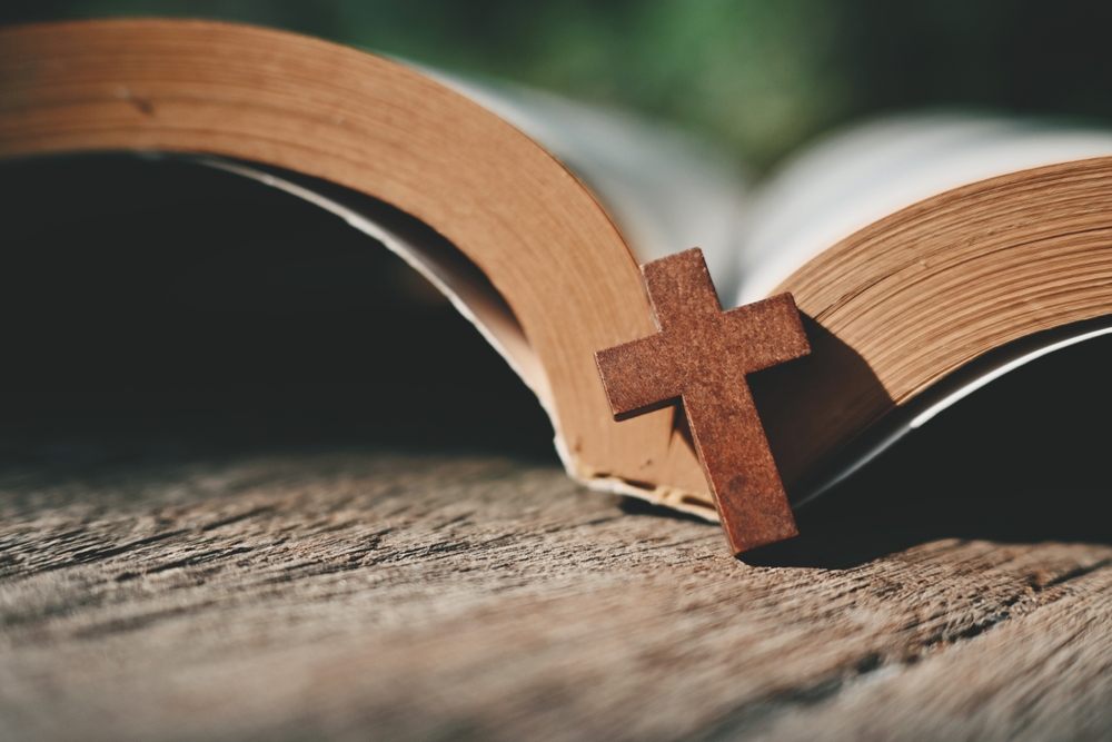 close up small cross and book on wood table, copy space for text