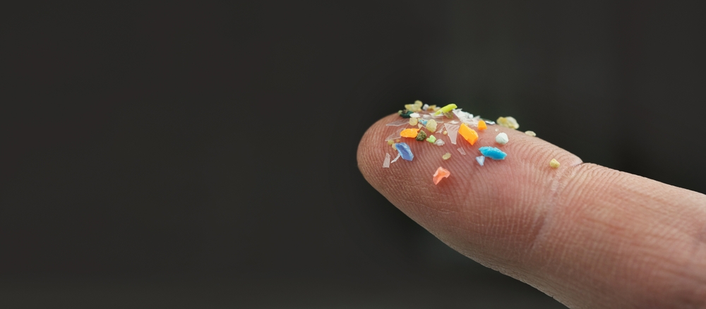 Macro shot of microplastics on a human finger. Concept of plastic pollution with nanoplastics. Soft focus on a microplastic particles that cannot be recycled with copy space on the right. Soft focus.