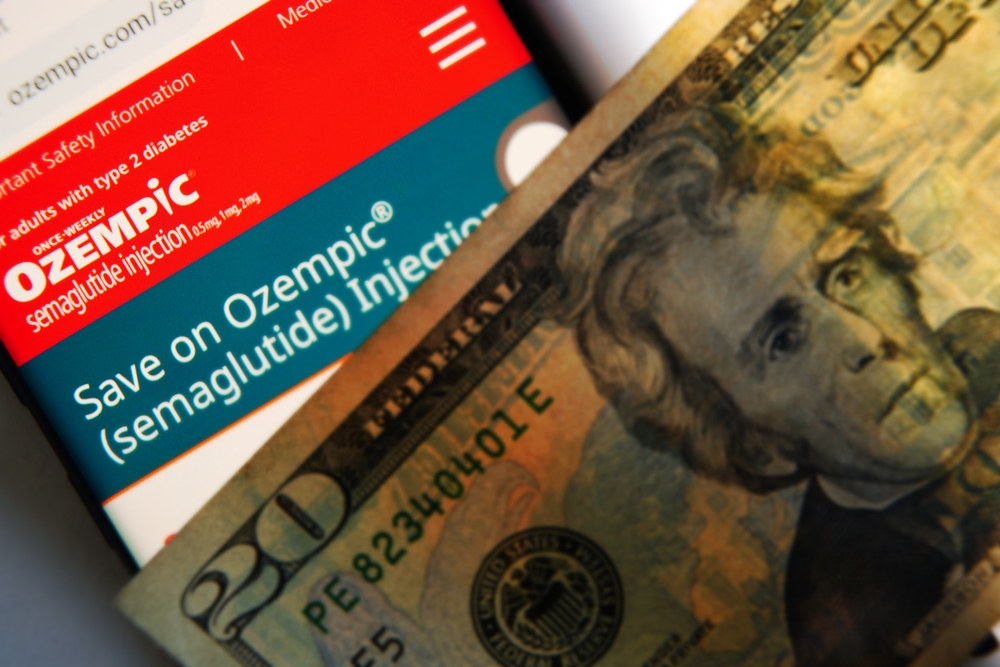 Raleigh, NC - USA - 08-15-2024: A cellphone with the Ozempic website displayed on the screen and a twenty dollar bill