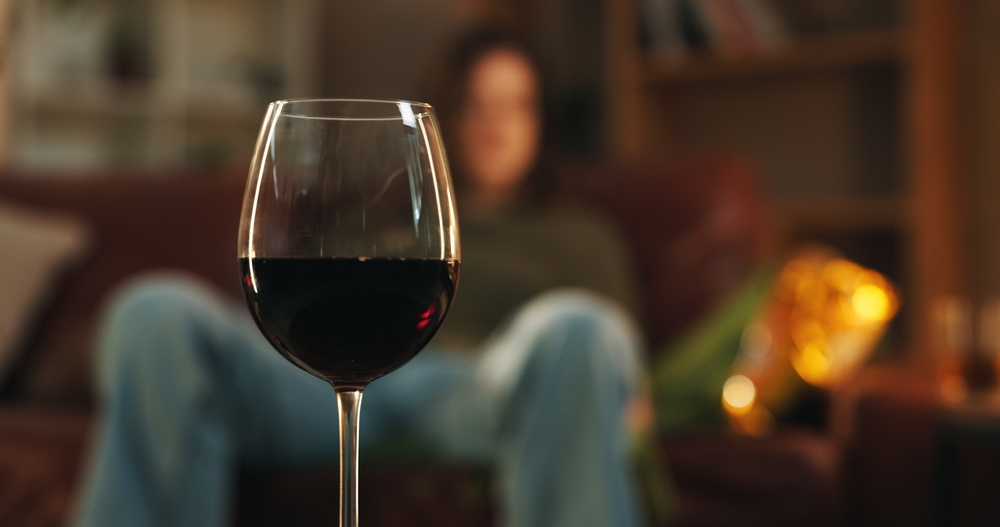House, glass and wine for alcohol addition at night in living room as stress relief or depression. Person, liquor and alcoholic with beverage or drink for problems, issues and substance abuse