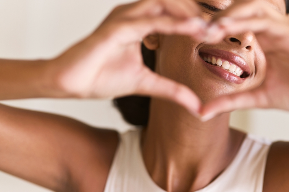 Dental Care Smile. Woman Making a Heart Shape with Her Hands, Emphasizing Happiness, Positivity, and Oral Health. Perfect for Wellness and Lifestyle Themes.