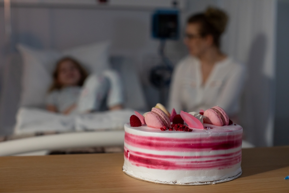A joyful celebration cake in a hospital room filled with a patient and a caring visitor close by
