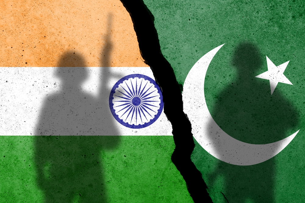 Flags of India and Pakistan painted on the concrete wall with soldier shadow. Kashmir crisis