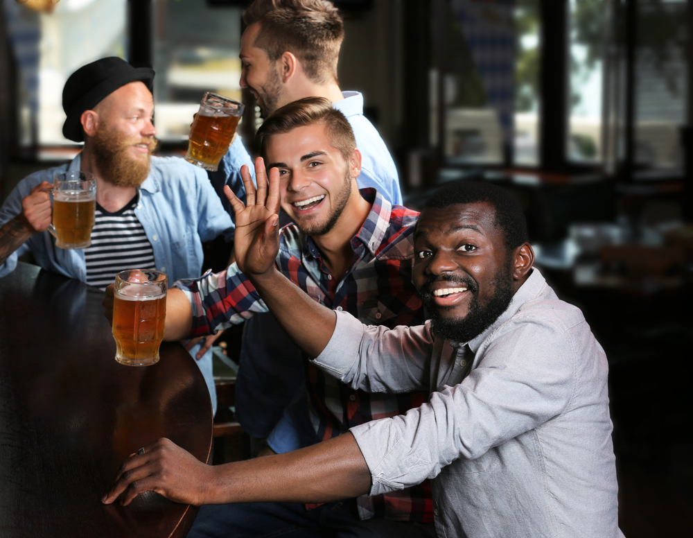 Happy friends having fun and drinking beer in pub