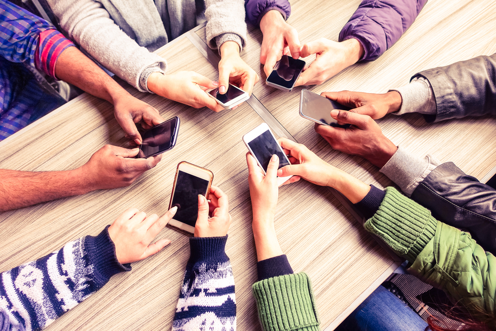 Top view hands circle using phone in cafe - Multiracial friends mobile addicted interior scene from above - Wifi connected people in bar table meeting - Concept of teamwork main focus on left phones
