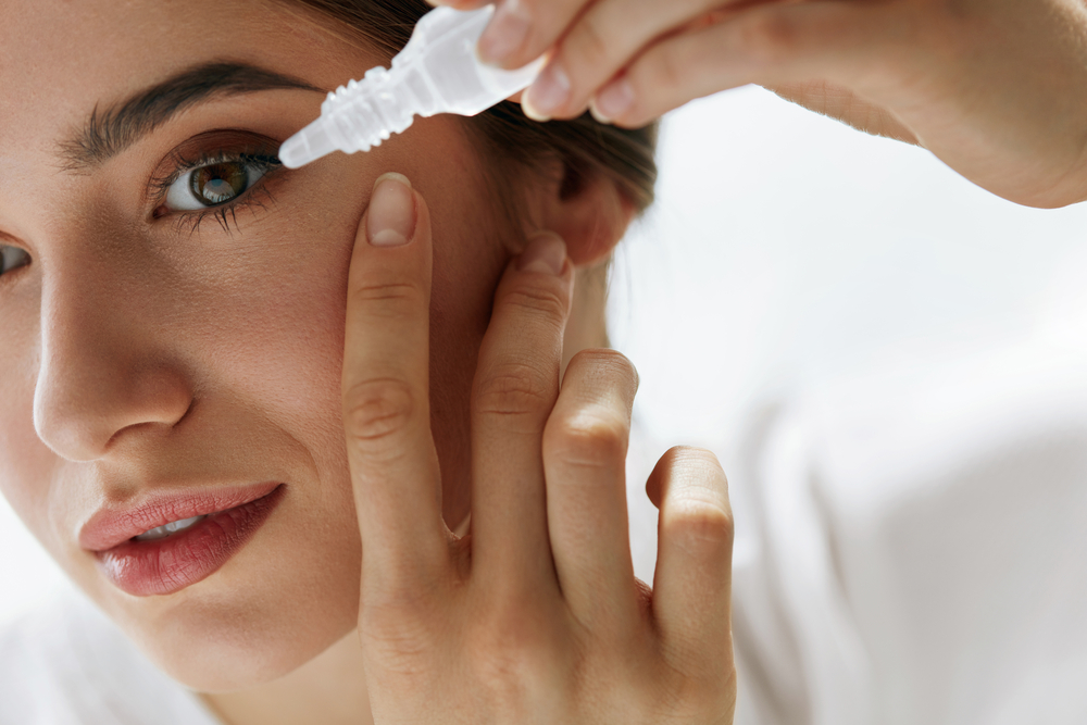 Vision And Ophthalmology Medicine. Closeup Of Beautiful Woman Applying Eyedrops In Her Eyes. Young Female Model With Natural Makeup Using A Bottle Of Eye Drops. Health Concept. High Resolution